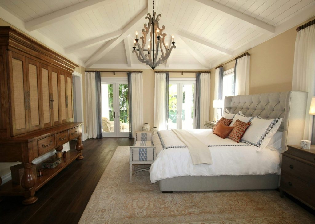 Stylish bedroom interior featuring a rustic chandelier, cozy bedding, and elegant wooden furniture.